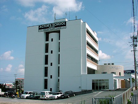 Fachada do prédio da Okinawa Actors School, com o letreiro 'Actor's School' no topo.